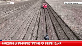 Agricoltori ucraini usano trattore per sminare i campi