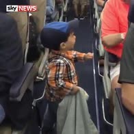 Two-year-old boy fist bumps plane passengers