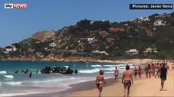Migrants arrive in dinghy on beach in Spain