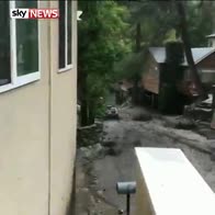 Car slides down hill in flowing mud
