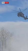 Military helicopter dislodges snow from trees