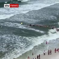 Beach goers form human chain to help swimmers